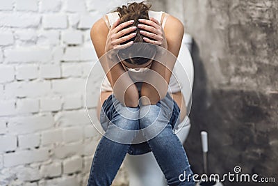 Woman Suffering From Constipation Sitting On Toilet In Restroom Indoors Stock Photo