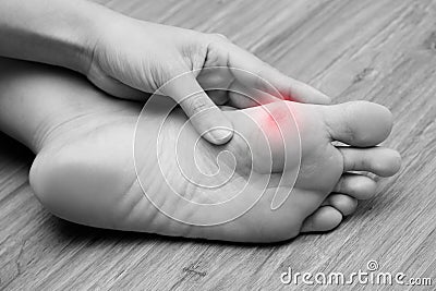 A woman suffering from corn on her foot sole. Black and white tone with red spot on her corn Stock Photo