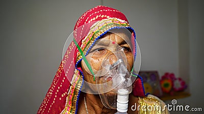 Woman suffering from Covid 19 disease. Old woman admitted in hospital and inhaling emergency oxygen with canula mask Stock Photo