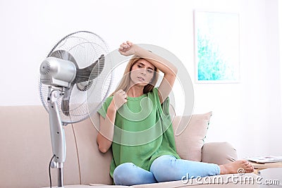 Woman suffering from heat in front of fan Stock Photo