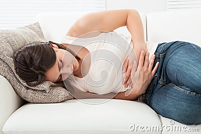 Woman suffering from stomachache on sofa Stock Photo