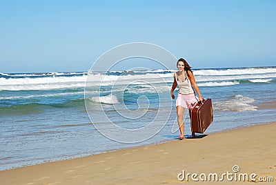 Woman with suitcase on beach Stock Photo