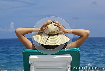 Woman sunbathing in a plastic chair on a beautiful Stock Photo