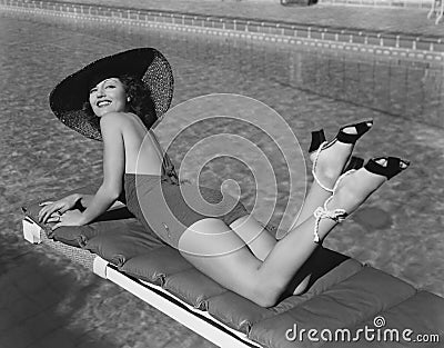 Woman sunbathing at pool Stock Photo