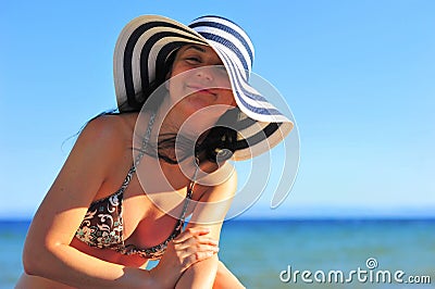 Woman sunbathing & wearing sun hat a the beach Stock Photo