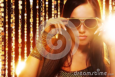 Woman in sunglasses over golden curtains Stock Photo