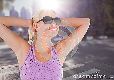 Woman in sunglasses stretching against blurry street with flare Stock Photo