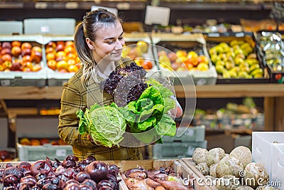 Woman in the supermarket. Beautiful young woman shopping in a supermarket and buying fresh organic vegetables Stock Photo