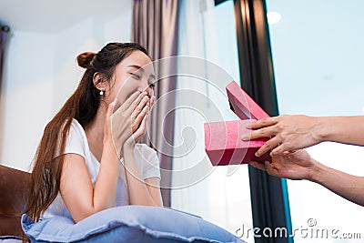 Woman surprised when looking at gift box on special day. Lovers and honeymoon concept. Happiness and Valentines day theme Stock Photo