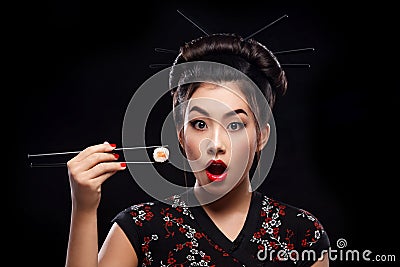 Surprised Asian woman eating sushi and rolls on a black background. Stock Photo