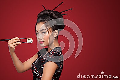 Asian woman eating sushi and rolls on a red background. 8 - Eight March, Black Friday, Setsubun Japanese Festival, sushi Stock Photo