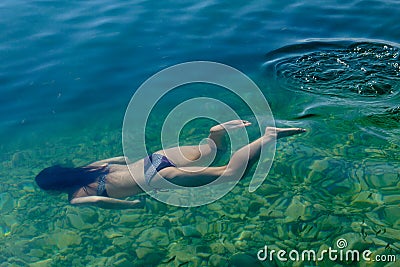 Woman swimming under water in clear lake with fish Editorial Stock Photo