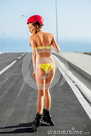 Woman in swimsuit with rollers on the highway Stock Photo