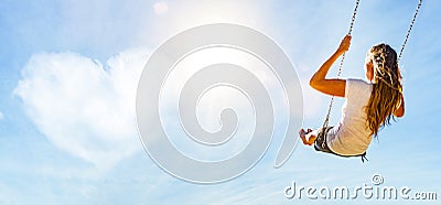 Woman on a swing with blue sky and heart-shaped cloud Stock Photo