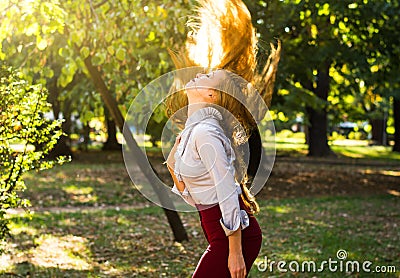 Woman swinging hair in the park, healthy hair concept Stock Photo