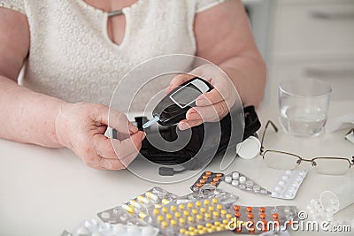 The woman at the table. Grandmother measures the level of glucose in the blood. Stock Photo