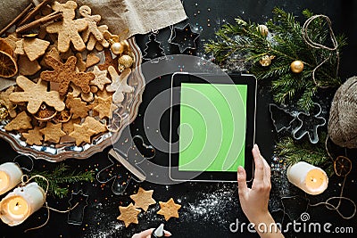 woman with tablet pc computer making gingerbread houses at home Stock Photo