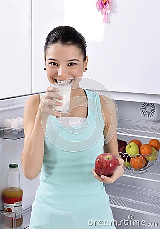 Woman take red apple and milk from fridge Stock Photo