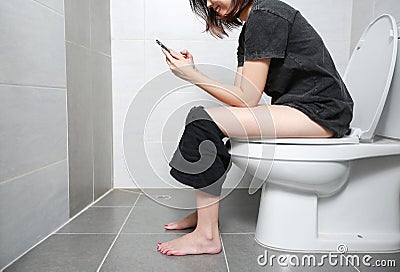 Woman take smart phone and smile happiness in the toilet. Stock Photo