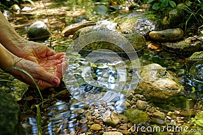 Woman take water in hand from Creek in forest, Mountain River in the wood Stock Photo