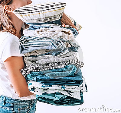 Woman takes in hands big pile blue and beige blankets, towels and other home textile Stock Photo