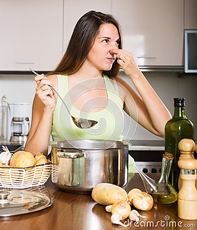 Woman takes lid off pan and feel musty smell Stock Photo