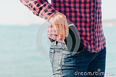 Woman takes out phone of her pocket on beach Stock Photo