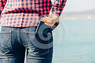 Woman takes out smartphone of her rear pocket of jeans Stock Photo