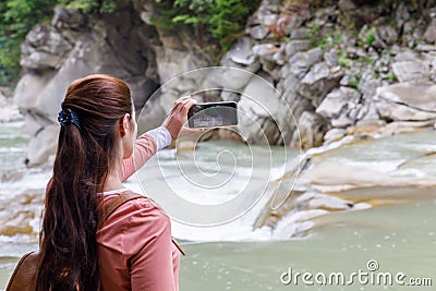 Woman takes pictures of the mountain river on the phone Stock Photo