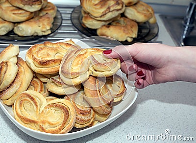 Woman takes tasty appetizing baked bun from the plate Stock Photo