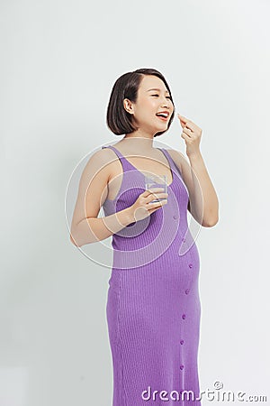 A woman takes vitamins during pregnancy. pregnant girl with a glass of water and a handful of drugs in her hand Stock Photo