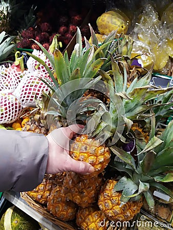 Woman takes yellow pineapple in market Stock Photo