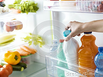 Woman taking a bottle of milk from the fridge Stock Photo