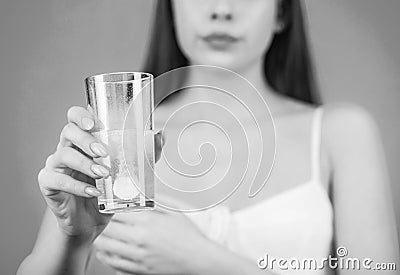 Woman taking drugs to releave headache. Brunette take some pills, holds glass of water, isolated on blue. Black and Stock Photo