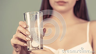 Woman taking drugs to releave headache. Woman take some pills, holds glass of water. Young woman taking pill against Stock Photo