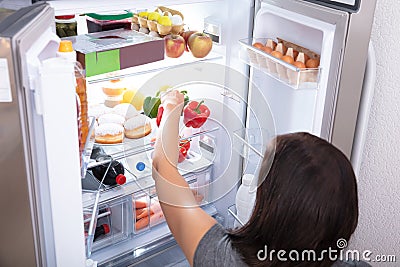 Woman Taking Food From Refrigerator Stock Photo