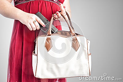 Woman taking gun from purse Stock Photo