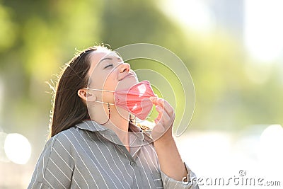 Woman taking off mask breathing fresh air outdoors Stock Photo