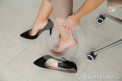 Woman taking off shoes in office, closeup. Tired feet after wearing high heels Stock Photo