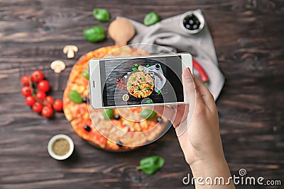 Woman taking photo of delicious Italian pizza with mobile phone Stock Photo