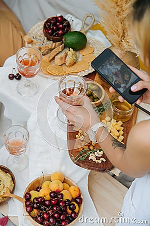 Woman taking picture of wine glass in hand over a table with various appetizers Stock Photo