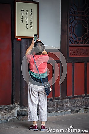 Woman taking pictures of chinese characters Editorial Stock Photo