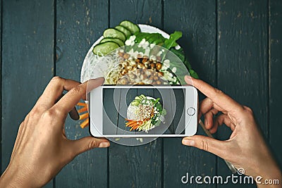 Woman taking pictures phobuddha bowl with vegan food, fried chickpeas, rice noodles with wegetables Stock Photo