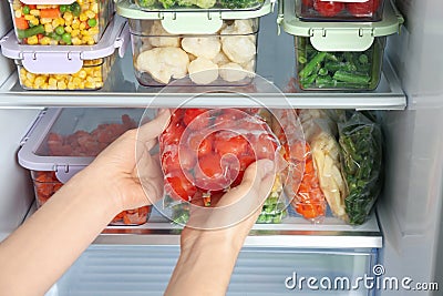 Woman taking plastic bag with tomatoes from refrigerator, closeup Stock Photo