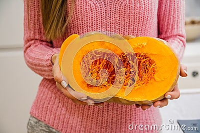 Woman taking seeds out of ripe cut pumpkin Stock Photo