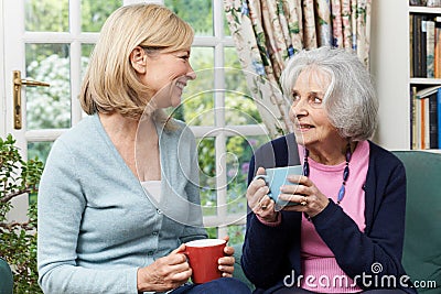 Woman Taking Time To Visit Senior Female Neighbor And Talk Stock Photo