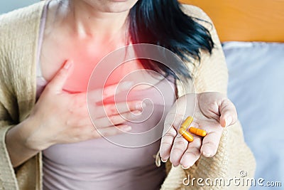 Woman taking turmeric pill, or curcumin herb medicine for GERD, treatment for heartburn from acid reflux disease Stock Photo