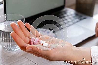 Woman taking Daily vitamins white working on laptop Organizer weekly shots Closeup of medical pill box with doses of Stock Photo