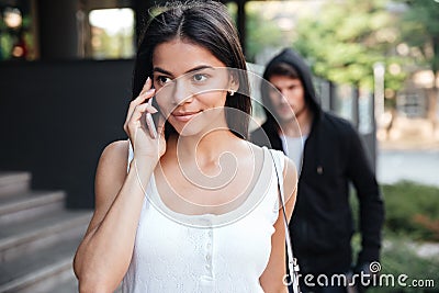 Woman talking on mobile phone and stalked by man criminal Stock Photo