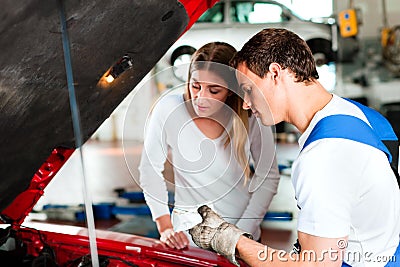 Woman talking to car mechanic in repair shop Stock Photo